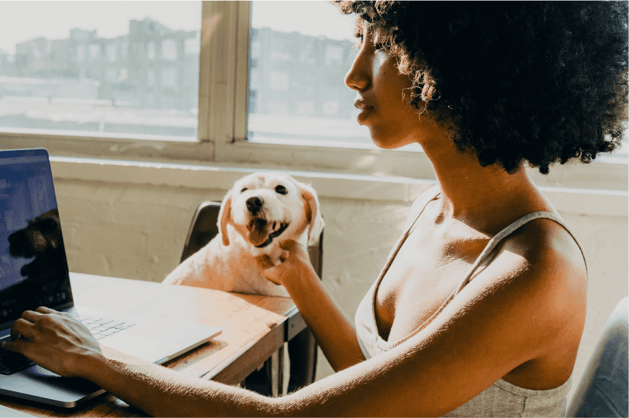 Mulher usando notebook ao lado de um cachorro