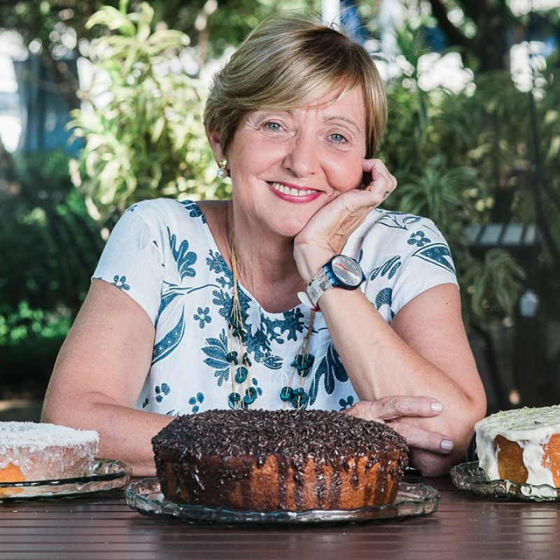 Foto de Alzira Ramos atrás de uma mesa com bolos